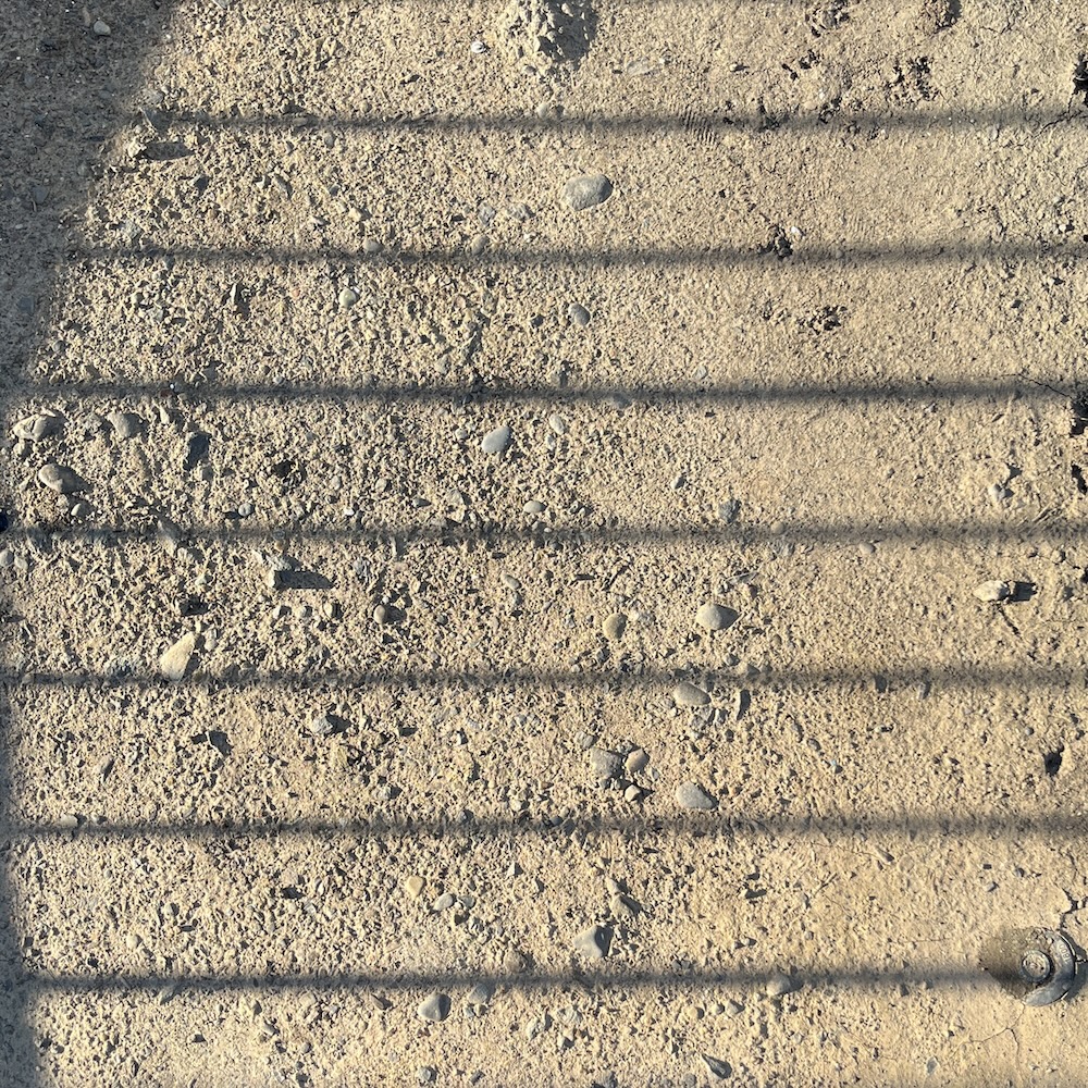 photo of dirt and rocks overlaid with thin horizontal shadows